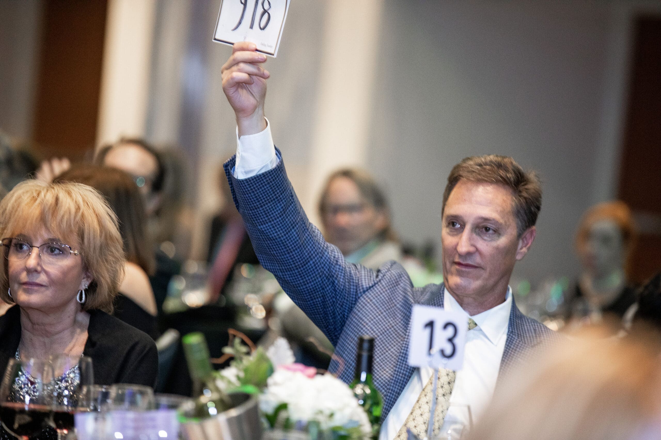 A man raising his hand with a number at a silent auction
